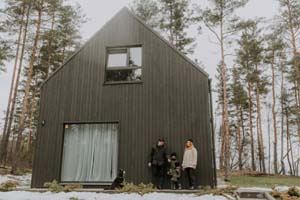Family Standing Outside A Black Modern Barndominium